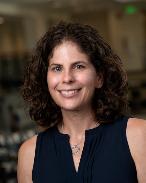 Smiling white woman with shoulder length curly brown hair.